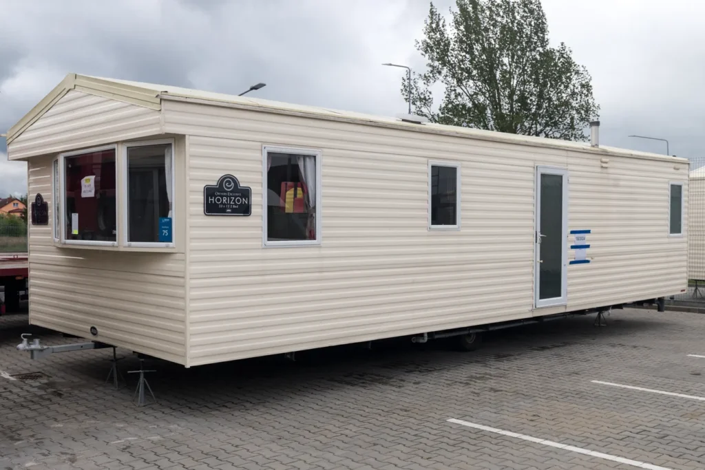 Angielski dom mobilny z białymi ramami okiennymi i białą podłogą, obok znak HORIZON